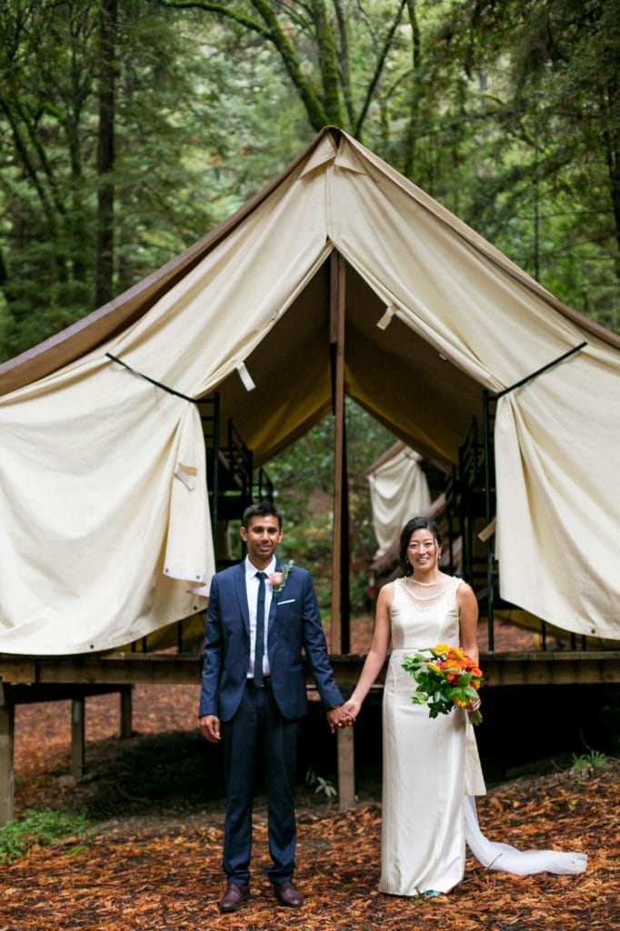 Groom and bride holding hands in front of a white tent