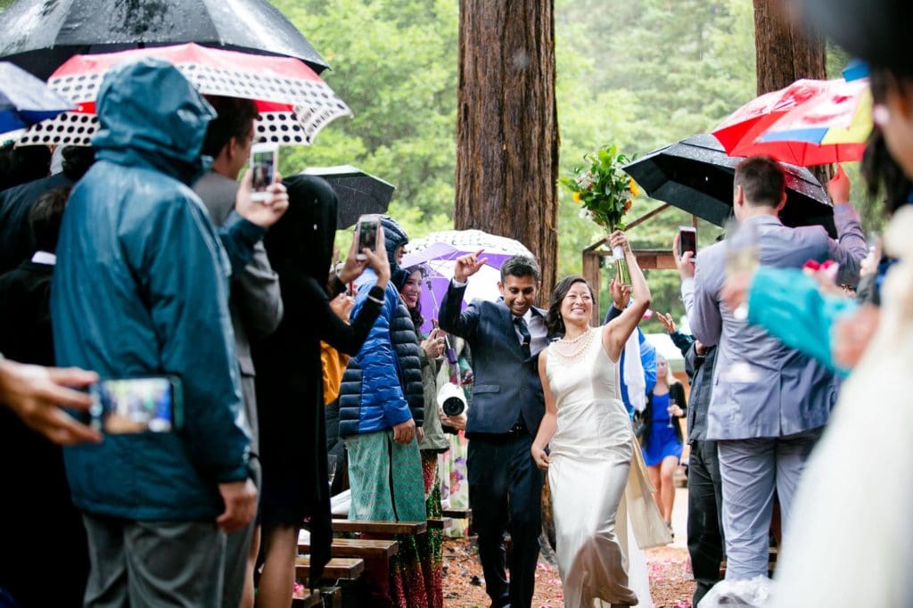 Bride and groom in the rain walking down the aisle together