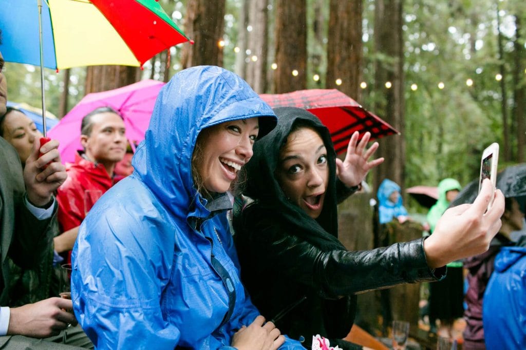 Guests having fun in the rain during a wedding ceremony
