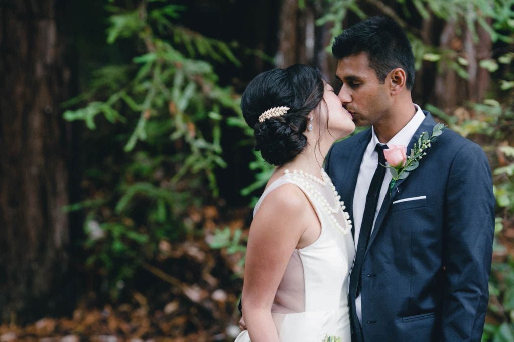 Bride and groom kissing in the woods