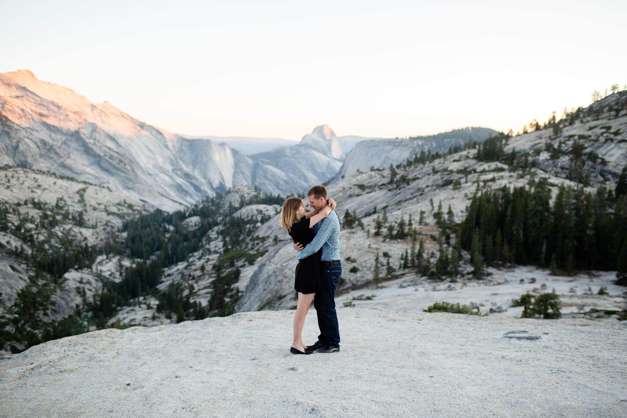 Man and Woman embracing at sunset on mountain with Half Dome in the background