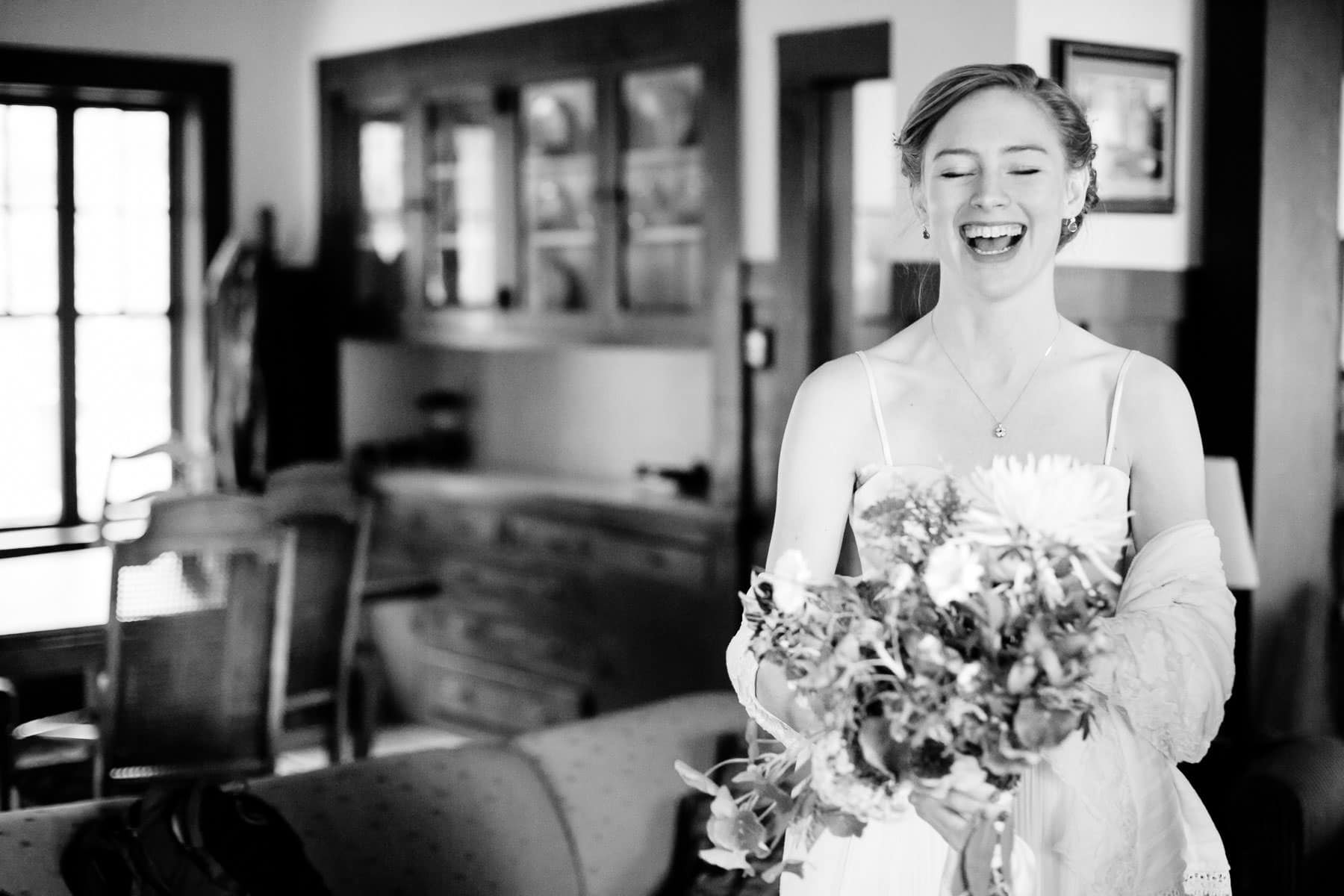 Black and white photo of a bride laughing while holding bouquet