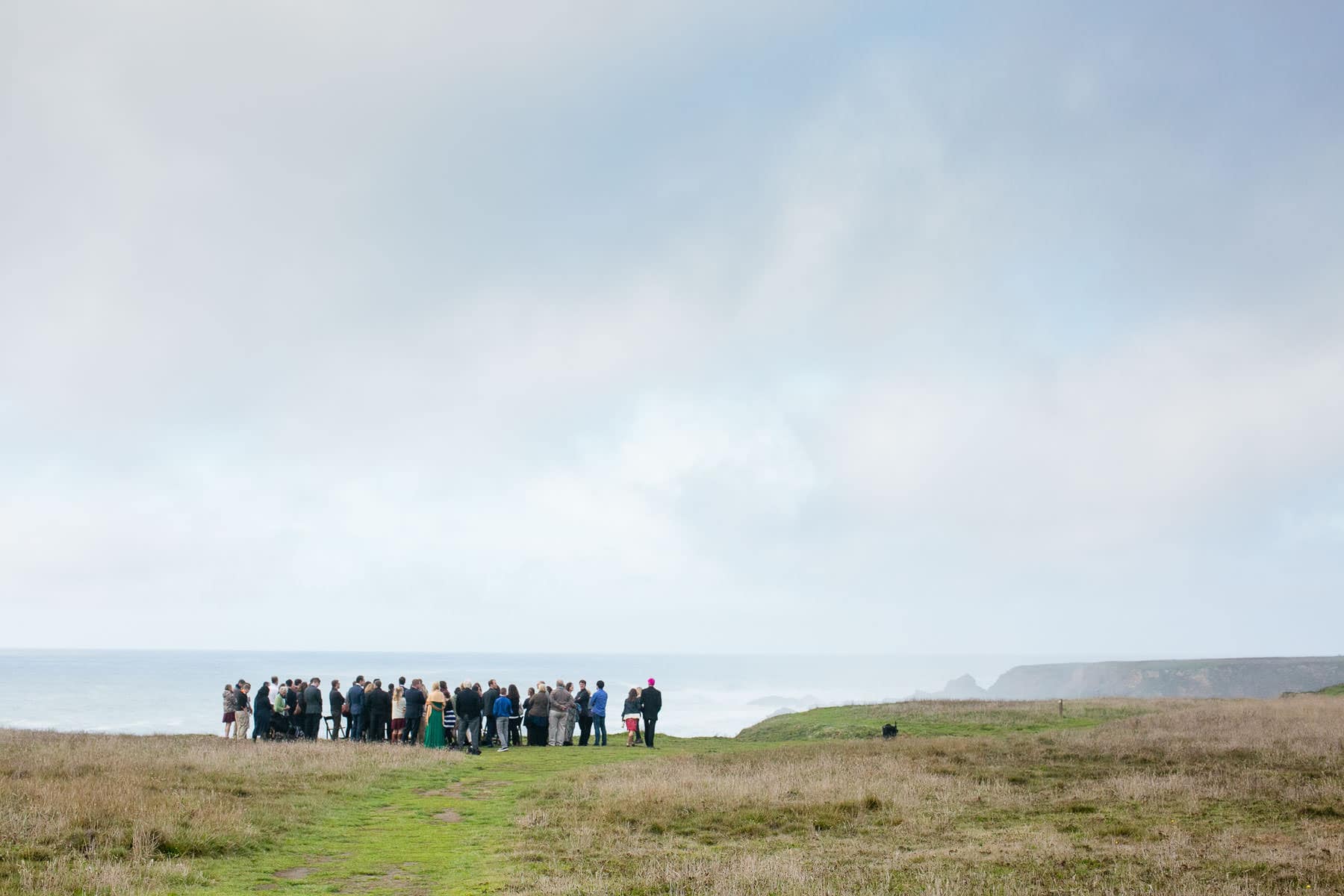 Large group of people standing in the distance on a bluff