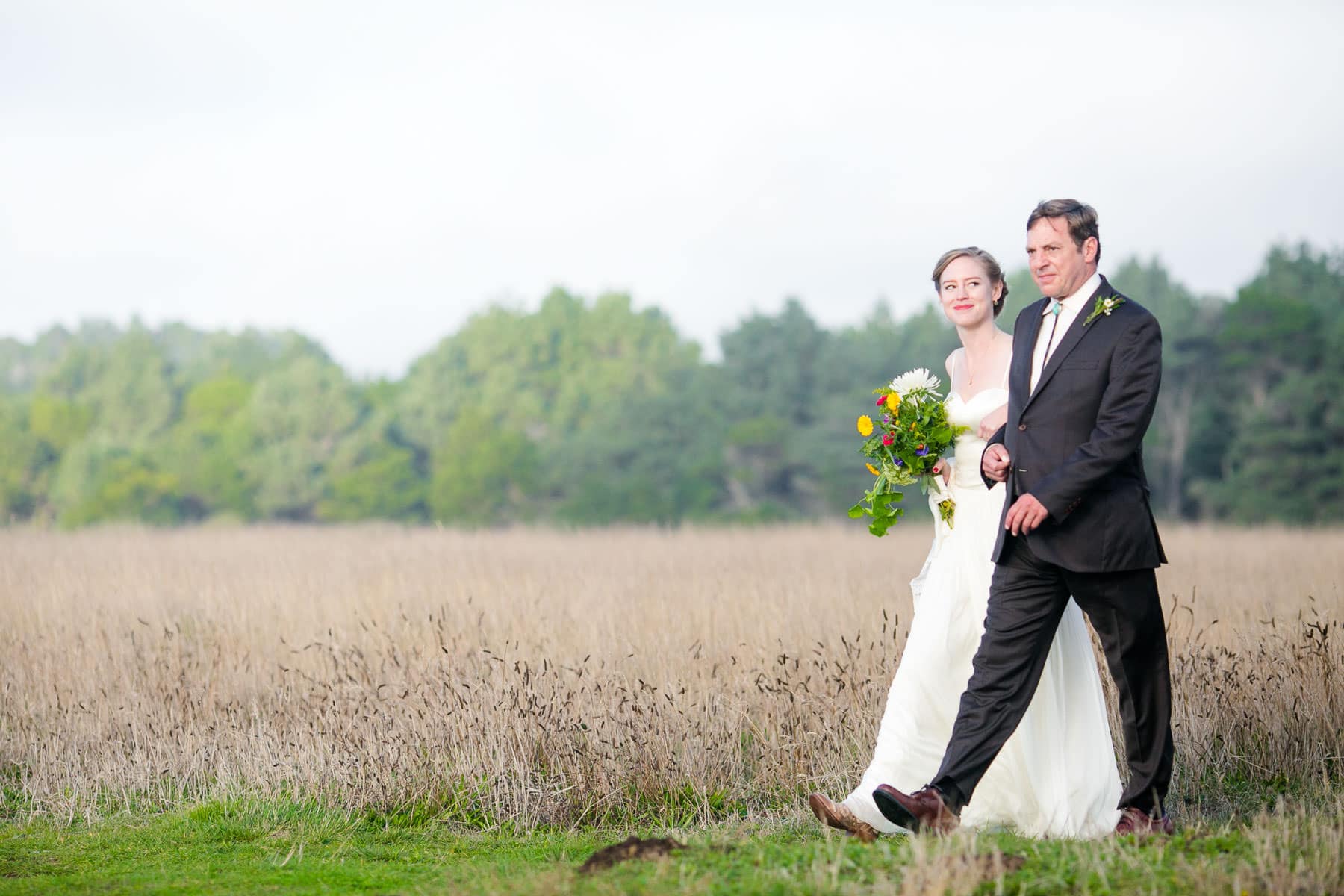 Bride and her father walking through a field