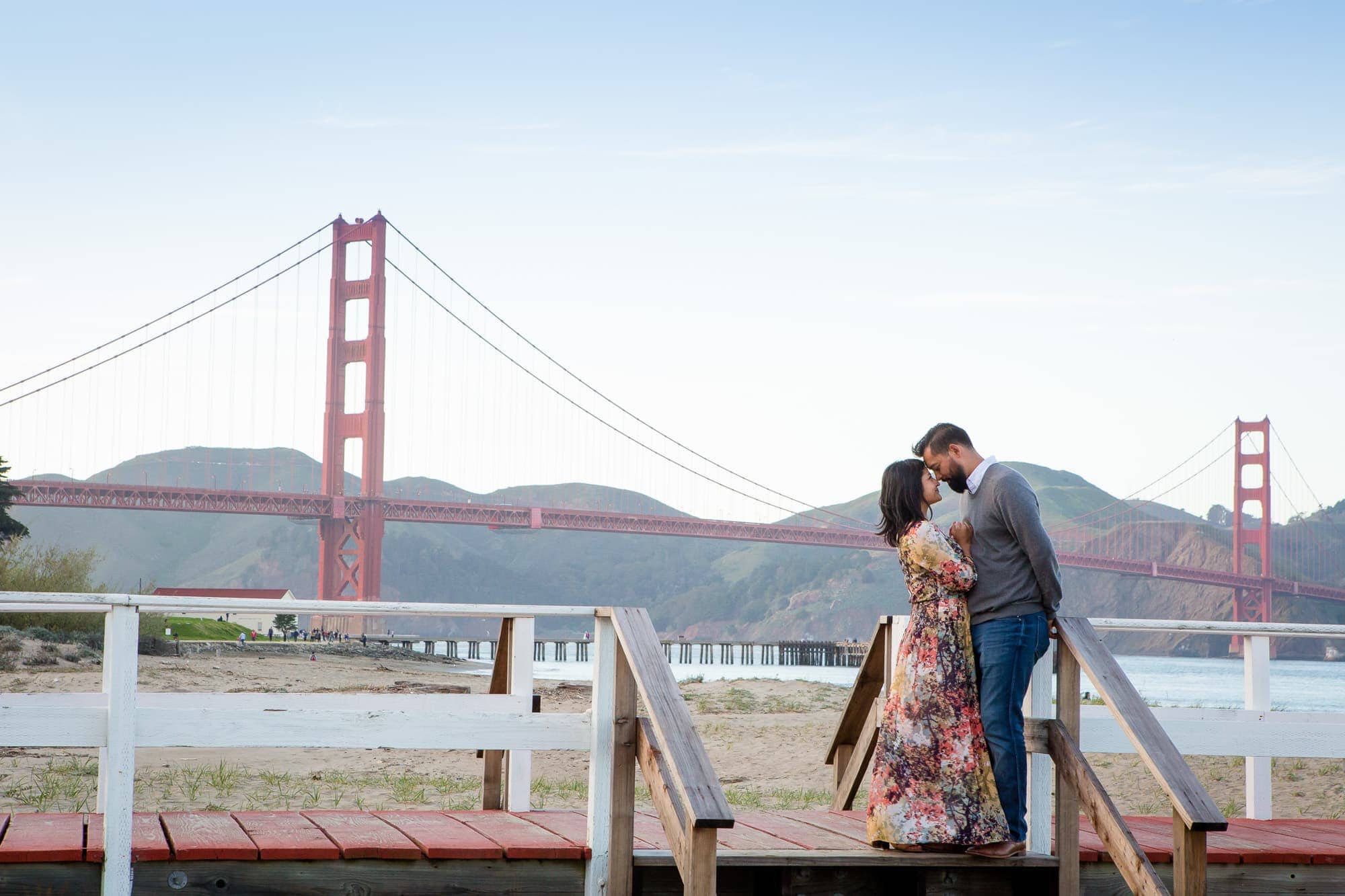 Couple embracing in front of Golden Gate Bridge in Crissy Field.