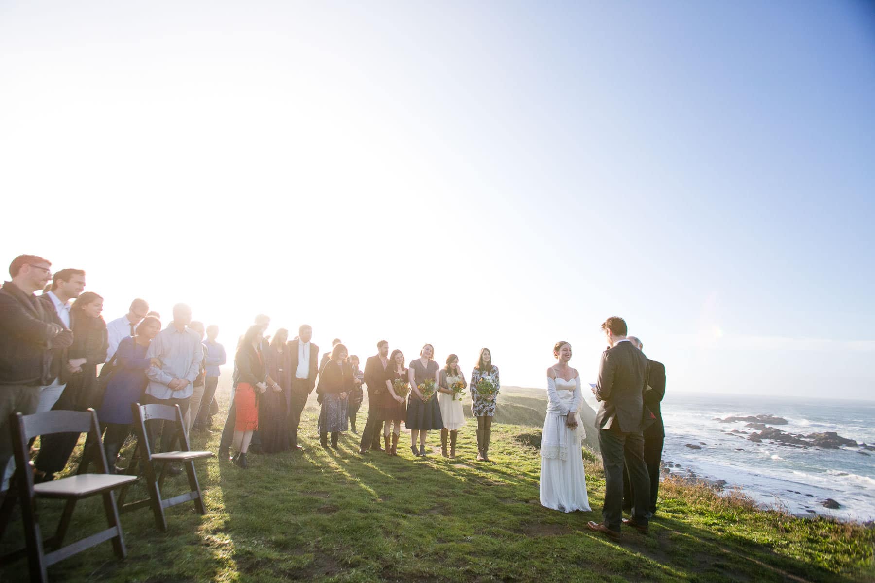 wedding guests and couple at wedding ceremony on bluff overlooking the ocean