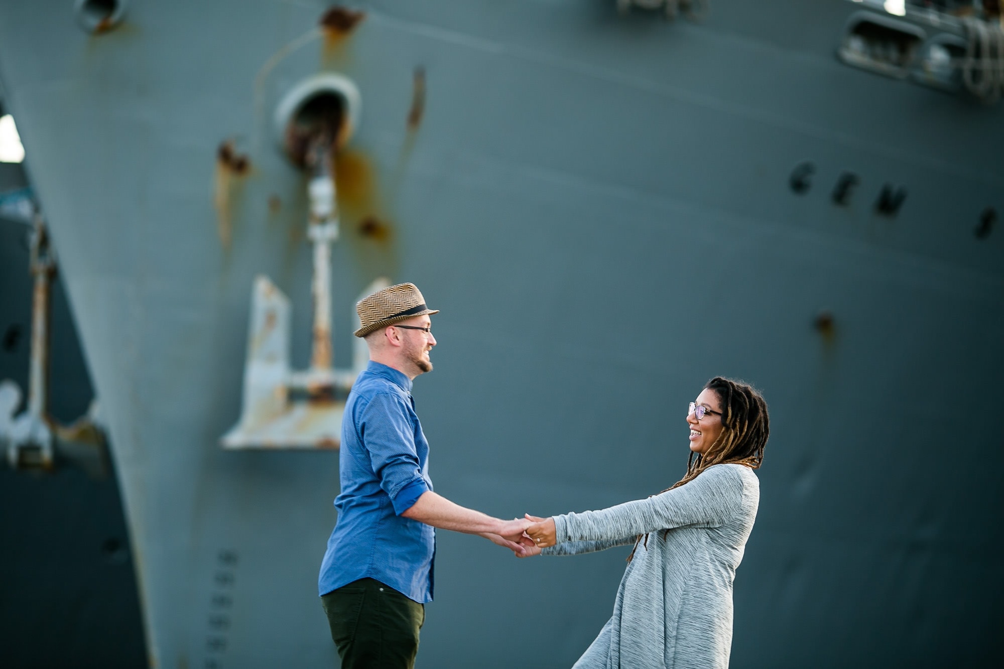Couple holding hands in front of large Navy Ship