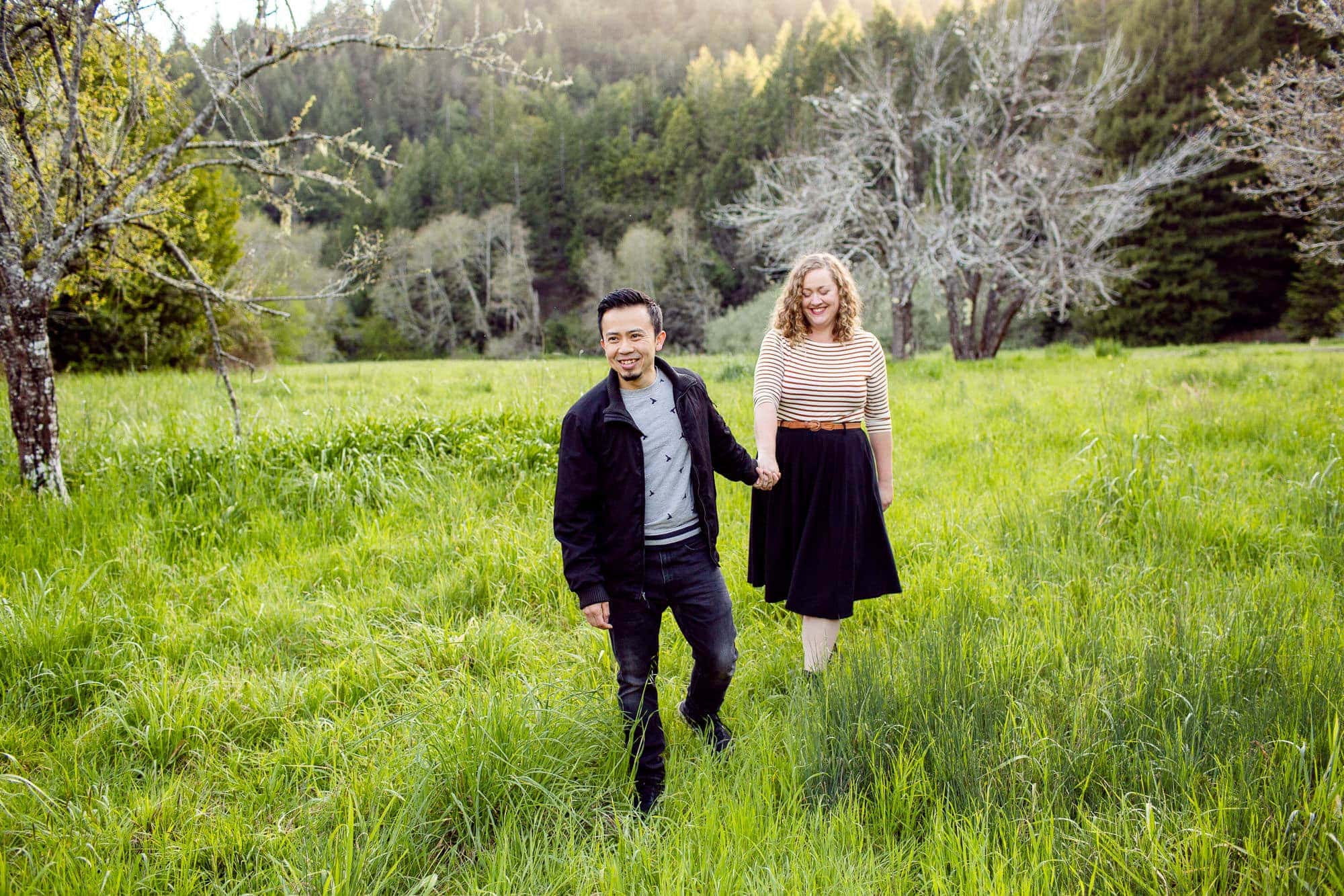 Couple walking in a clearing in the woods with green grass