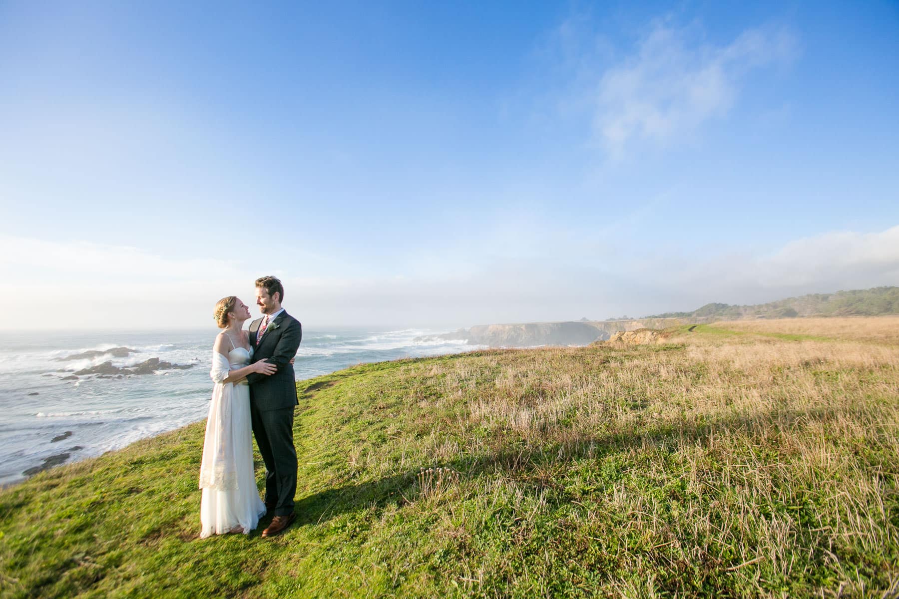 Bride and groom on bluff overlooking the ocean