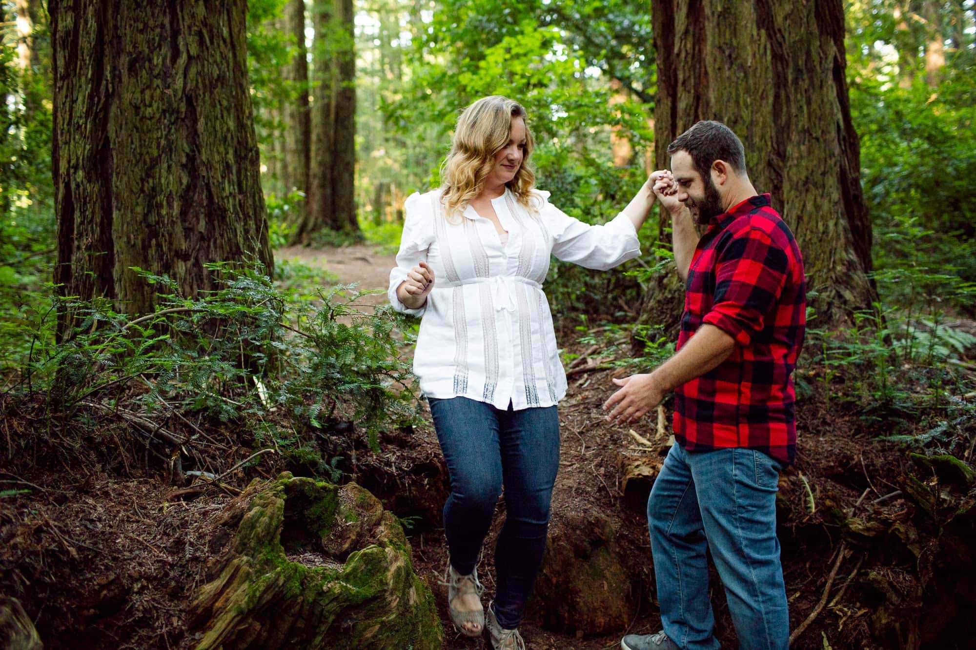 Man helping woman down a path in the redwood forest