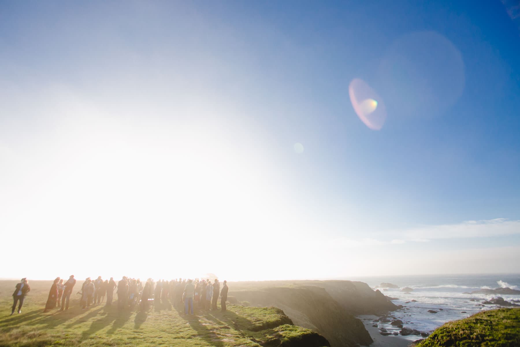 Large group of people off in the distance on a bluff overlooking the ocean