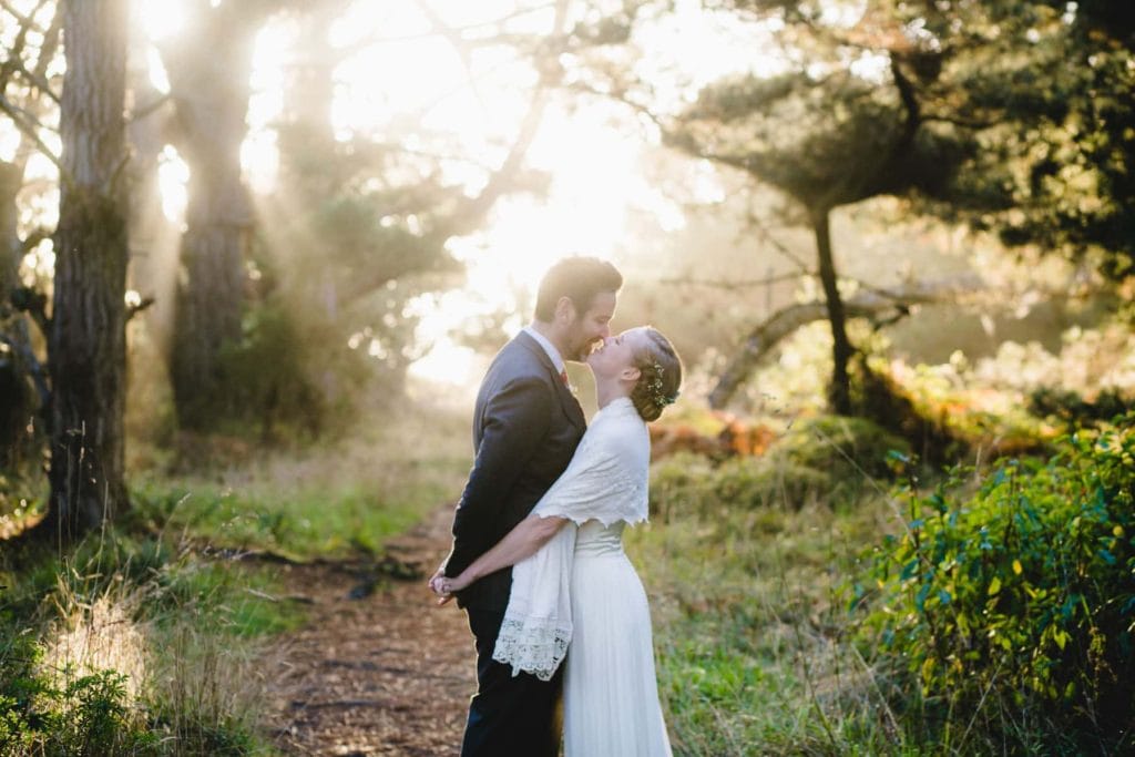 Man and woman embracing in the woods at sunset