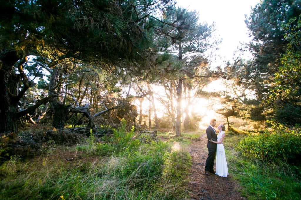 Man and woman embracing in the woods at sunset in wedding clothes