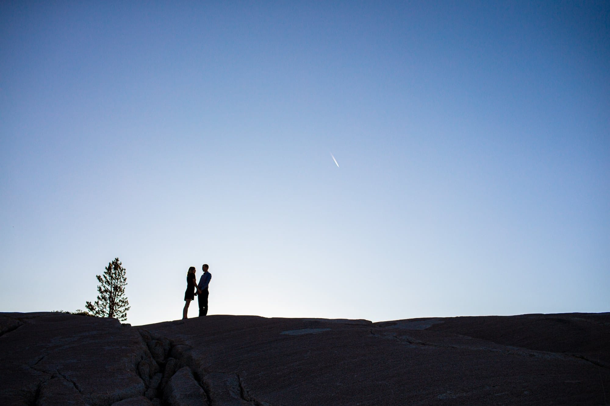 Silhouetted Couple on mountain with blue sky