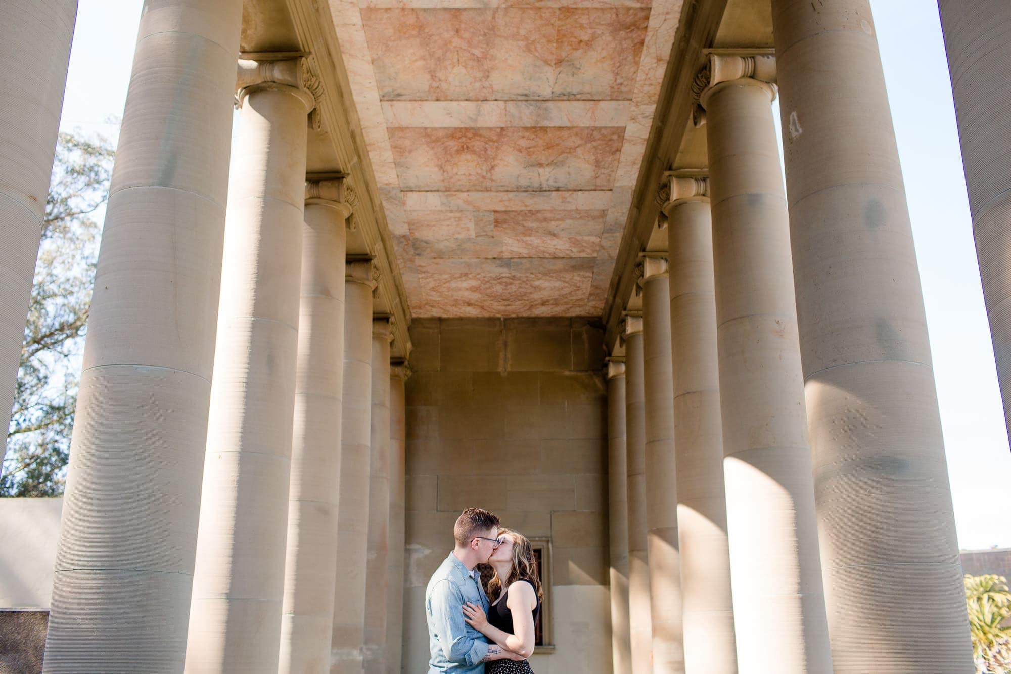 Couple kissing in between two rows of pillars