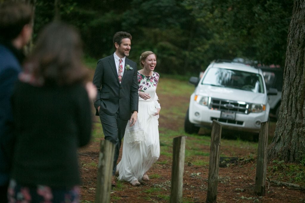 Groom and Bride walking into outdoor forest wedding reception