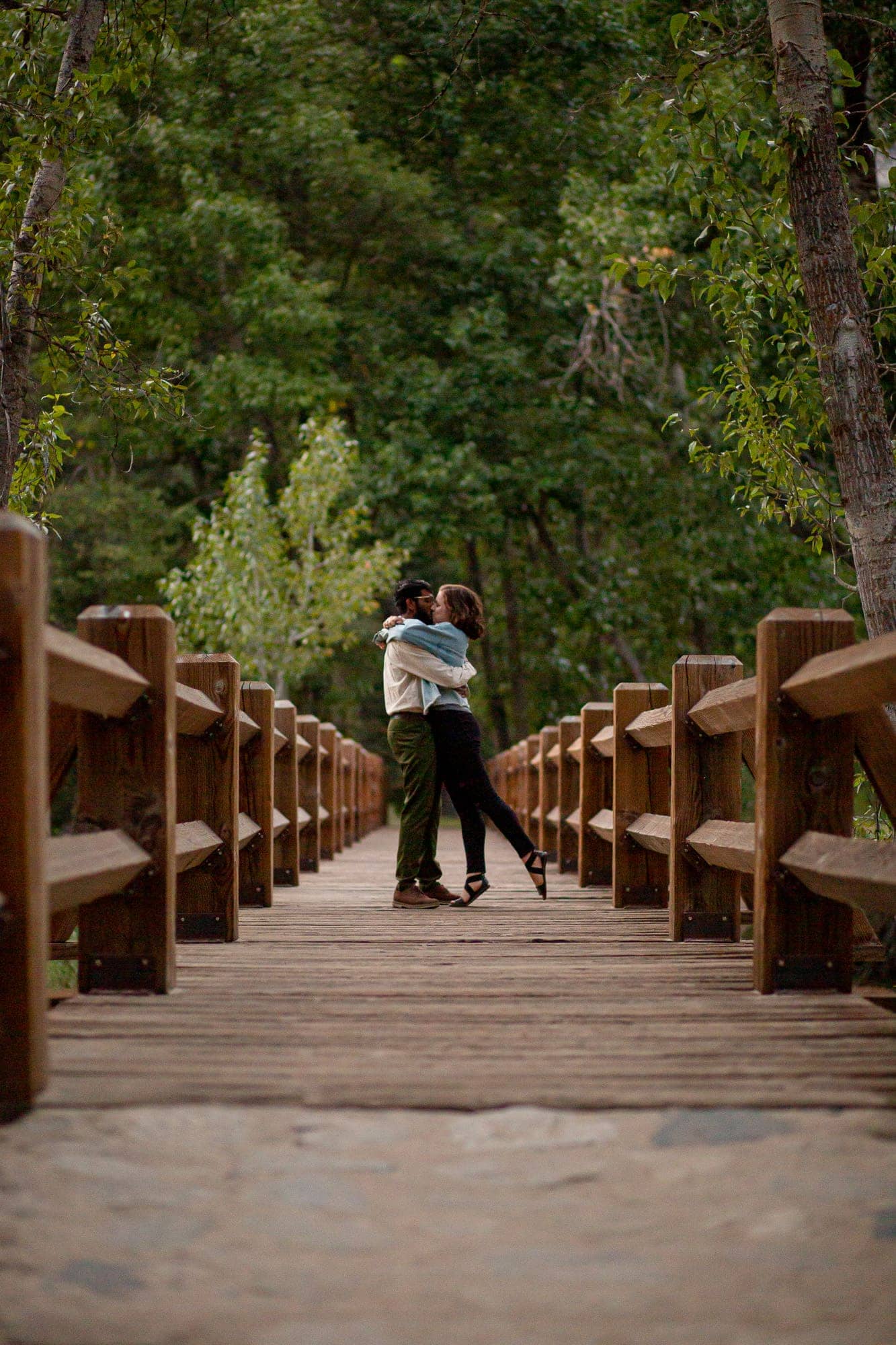 Couple kissing on a brown bridge