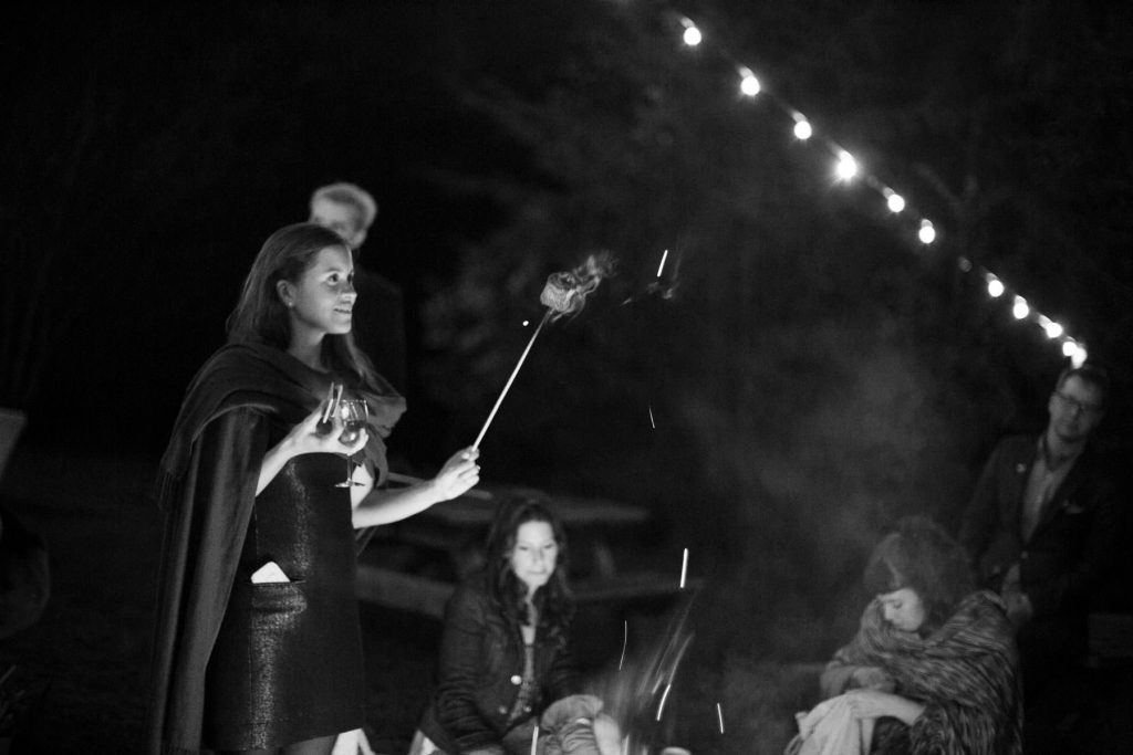 Woman making roasted marshmallows by a campfire in black and white