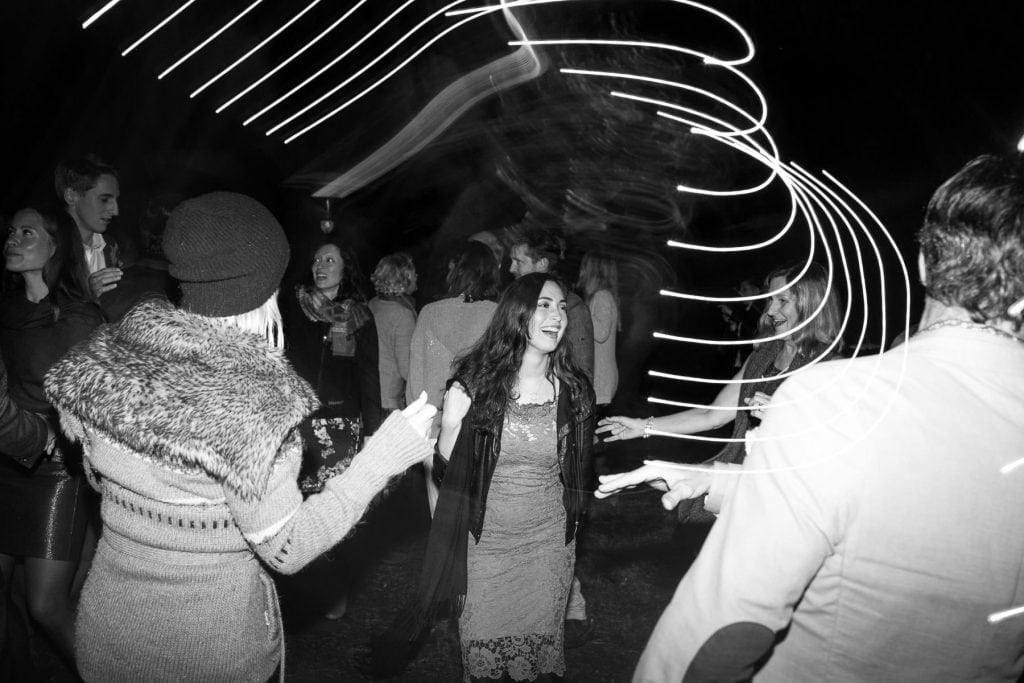 three people dancing at wedding reception outside at night