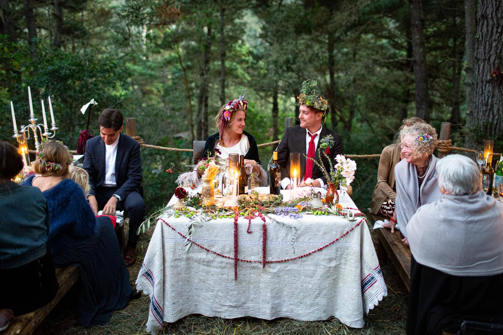 Bohemian Newlyweds at sweetheart table outside looking at each other during wedding reception