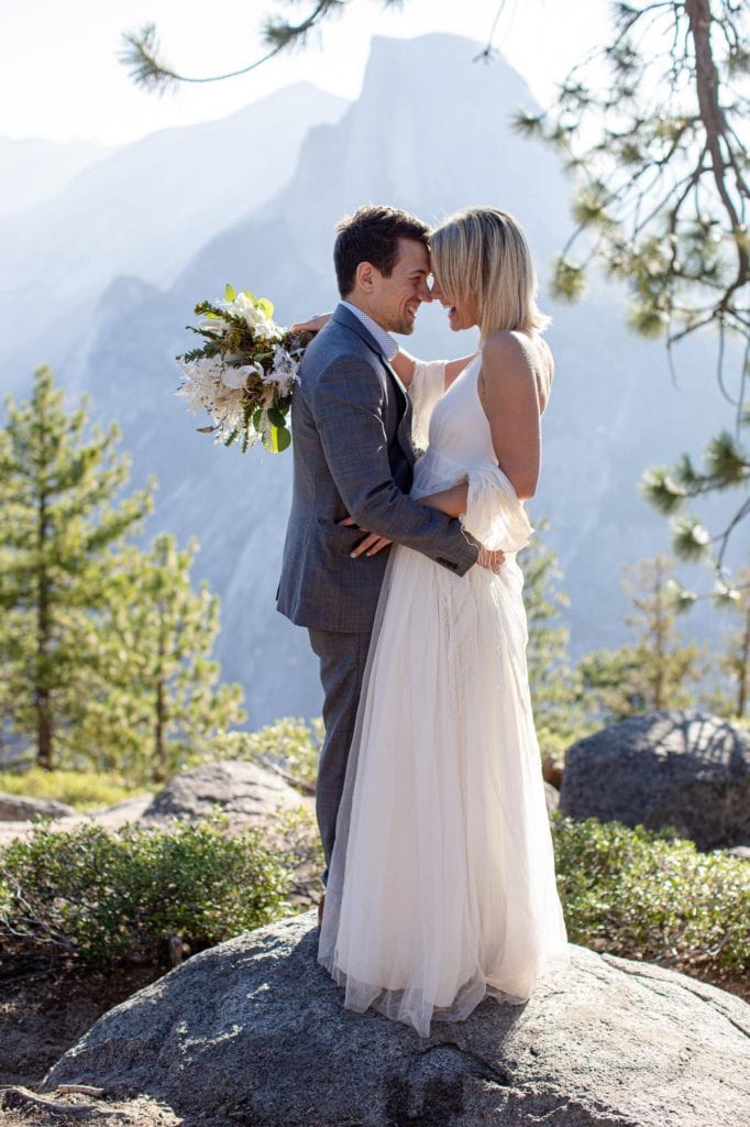 Adventure elopement with groom and bride looking at each other laughing with Half Dome in the backgroun in Yosemite