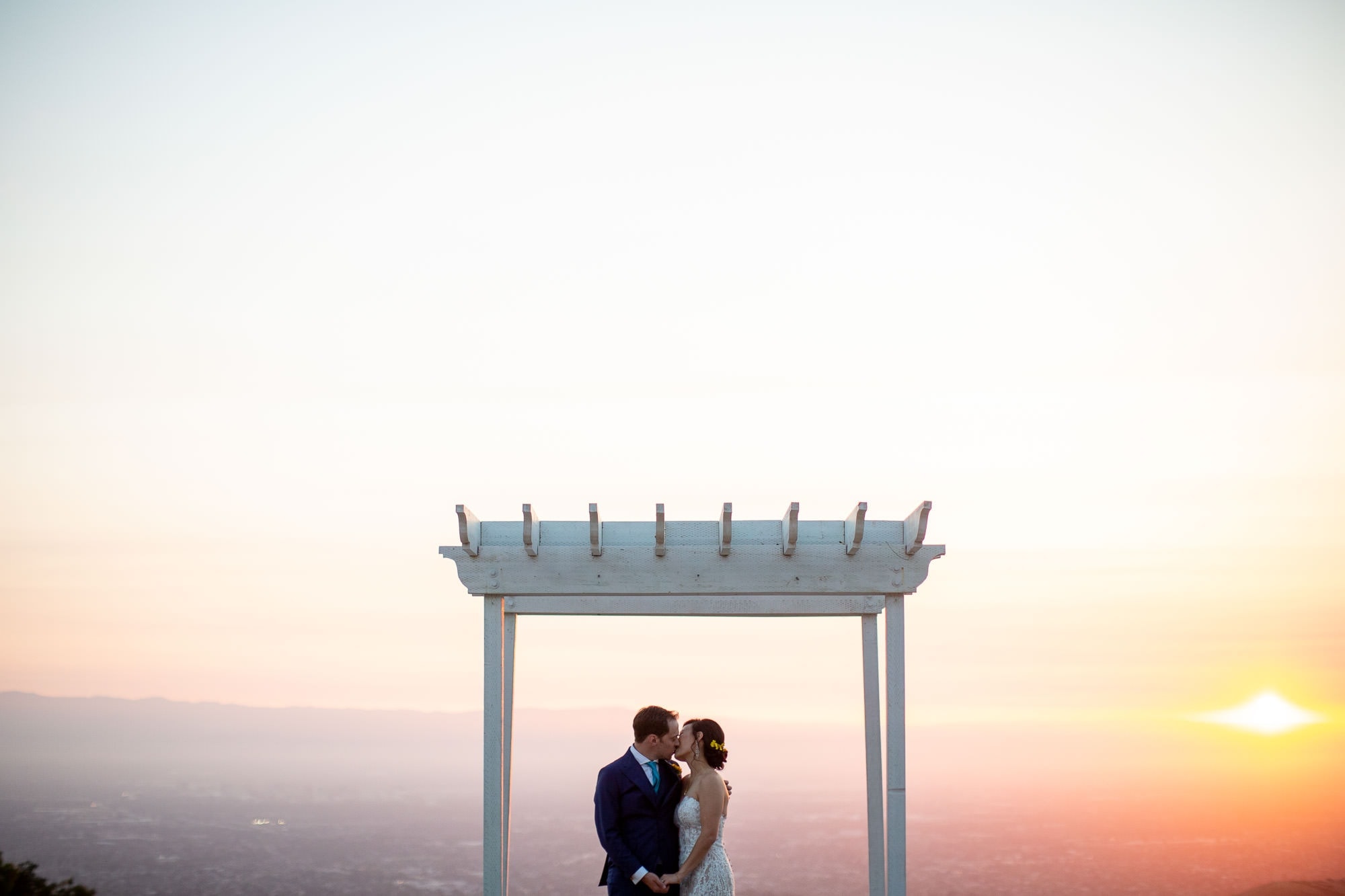 San Jose Bride and groom kissing under gazebo in San Jose Hills with sunset in the background