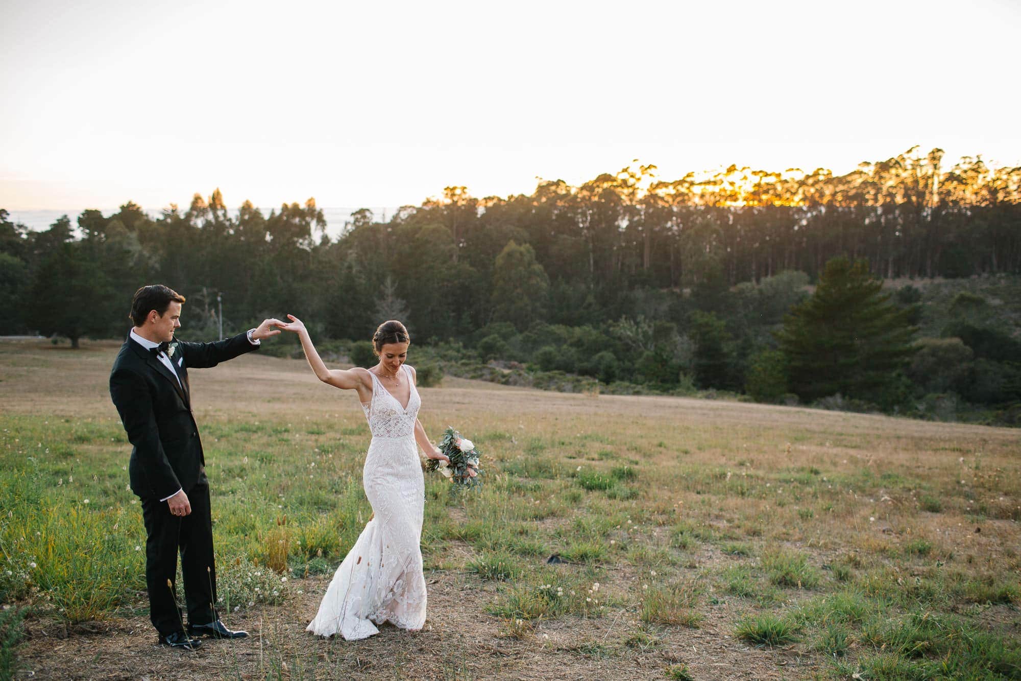Groom and bride dancing on a hill at sunset in Pescadero California