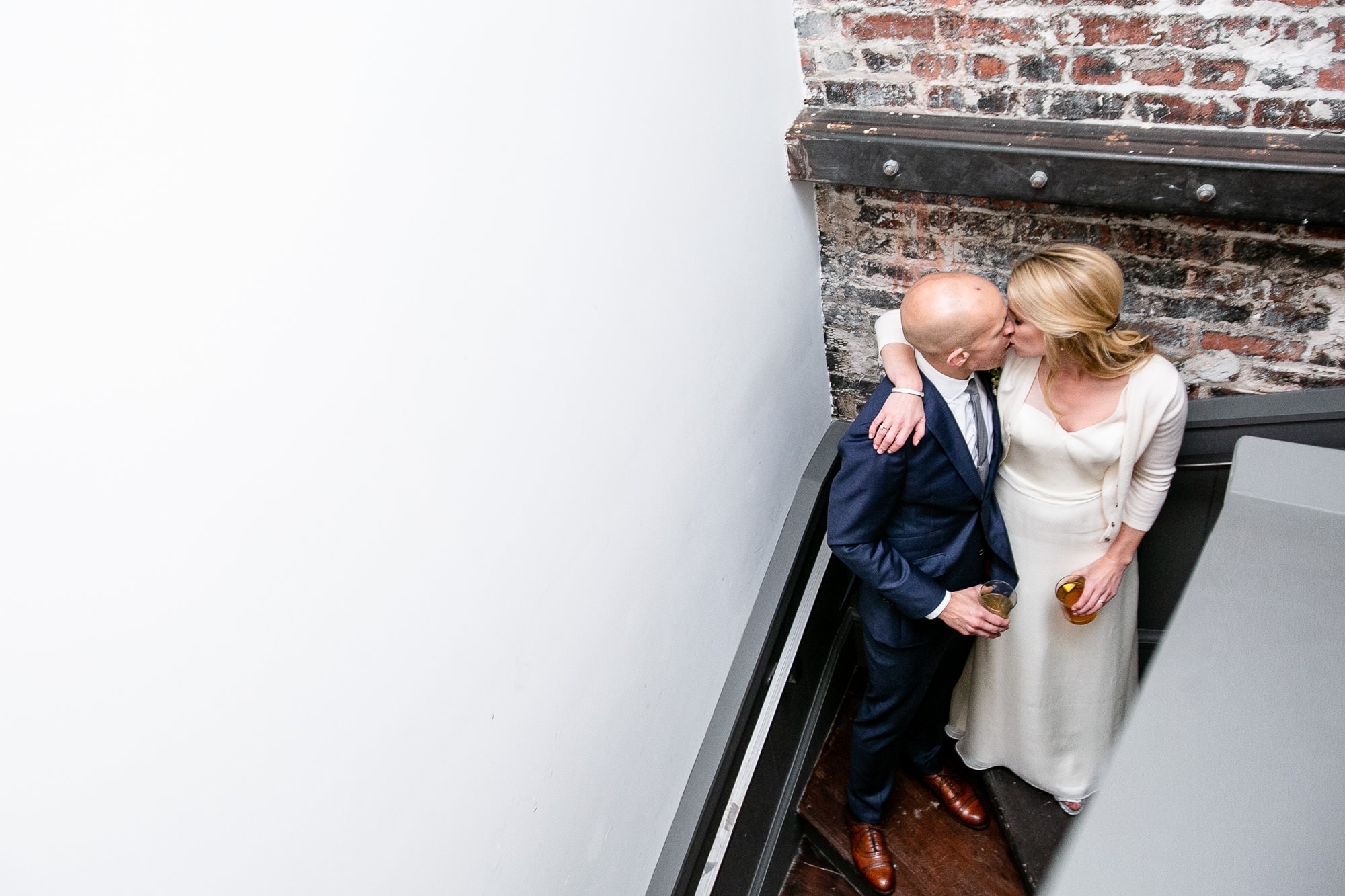 San Francisco couple sneak a kiss in a stairway during their wedding reception