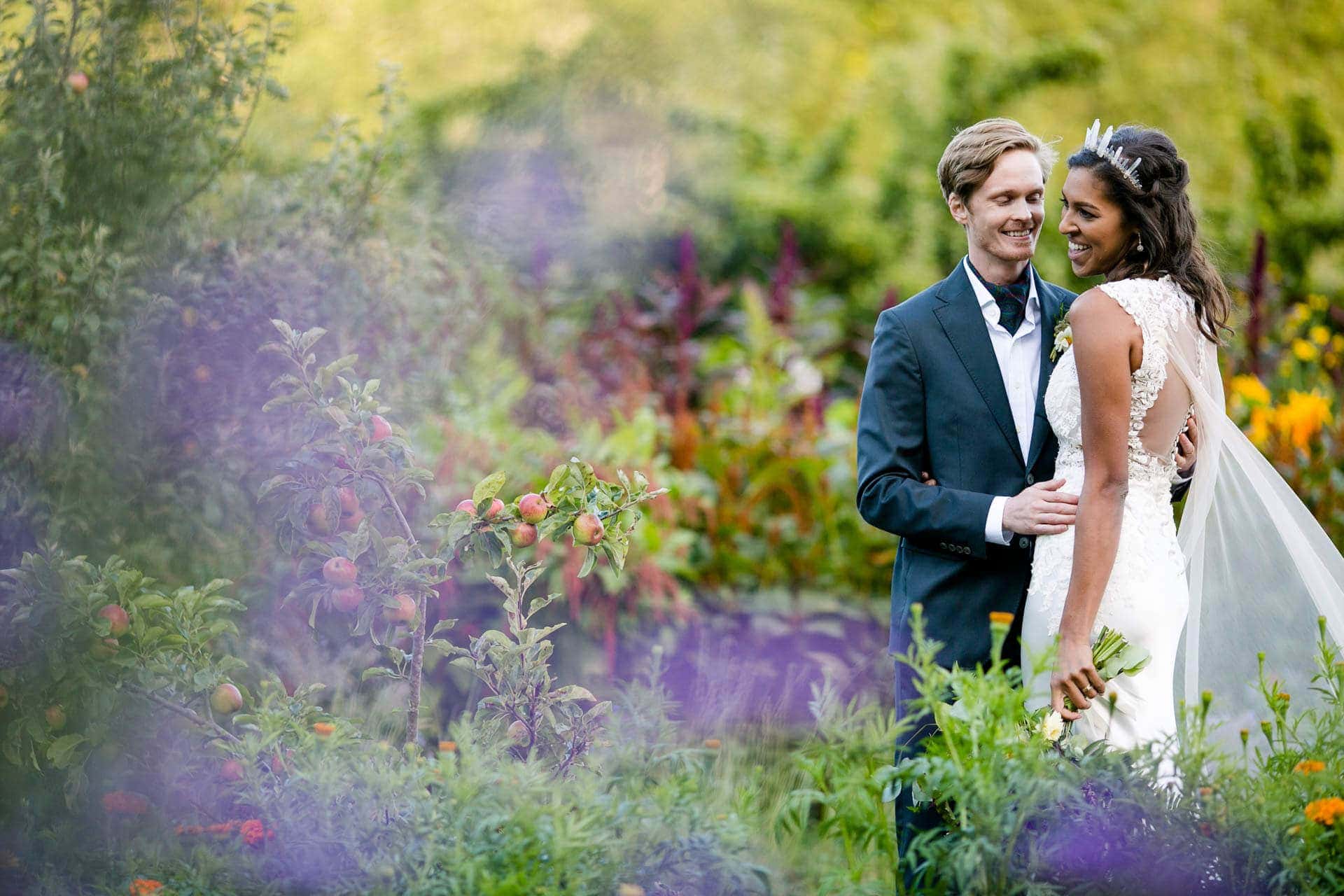 Bride with a crystal crown and groom standing in a floral garden at Oz Farm
