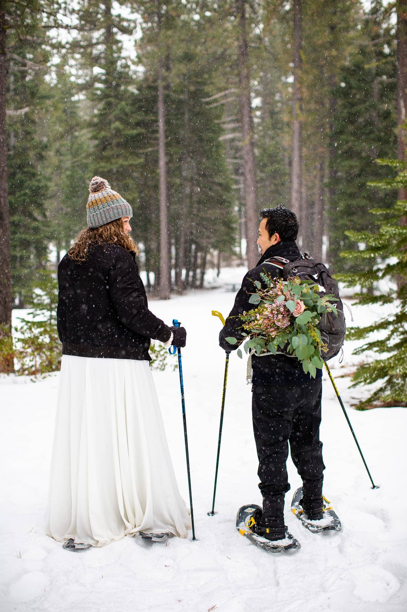 Snowy adventure elopement photo of bride and groom hiking in snowshoes