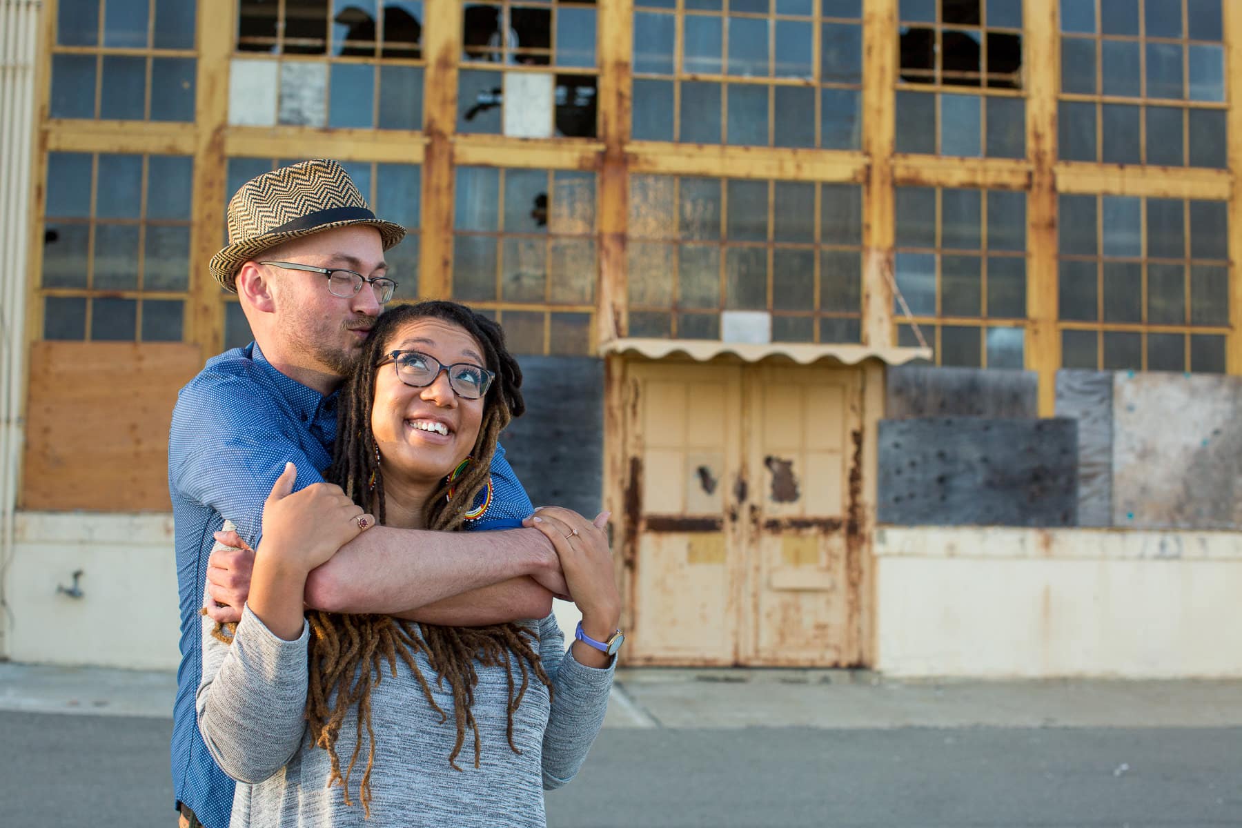 Two people embracing in front of abandoned warehouse