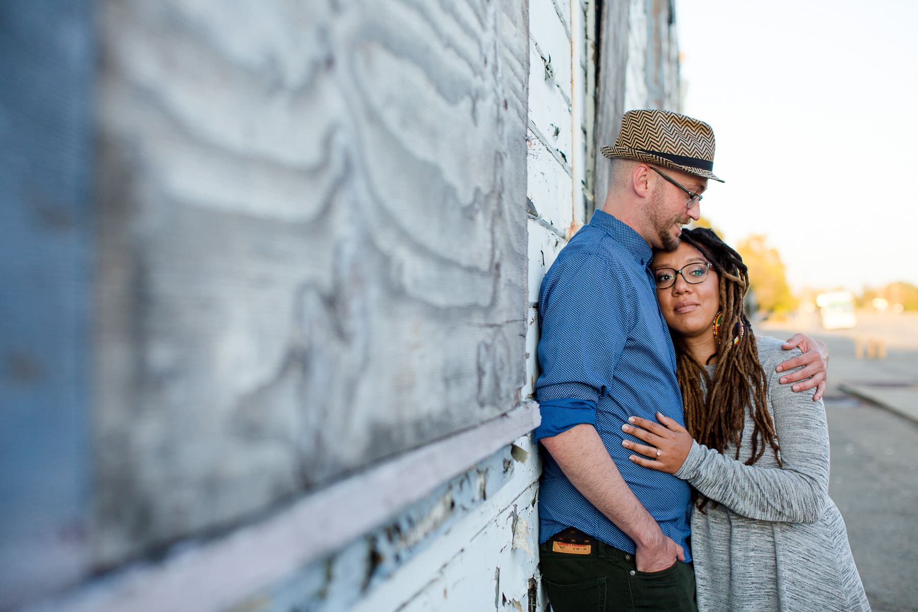 Man and woman hugging and leaning on an old blue building
