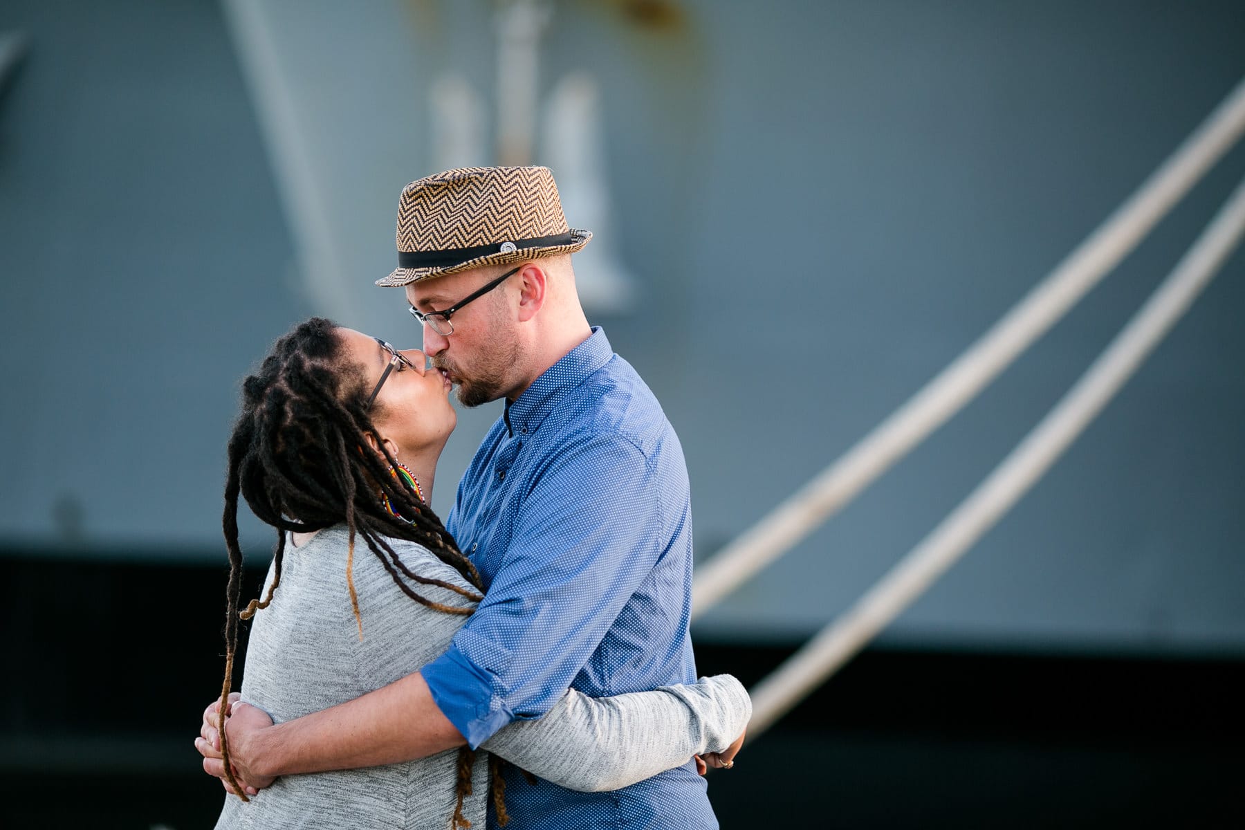 Couple kissing in front of large navy ship