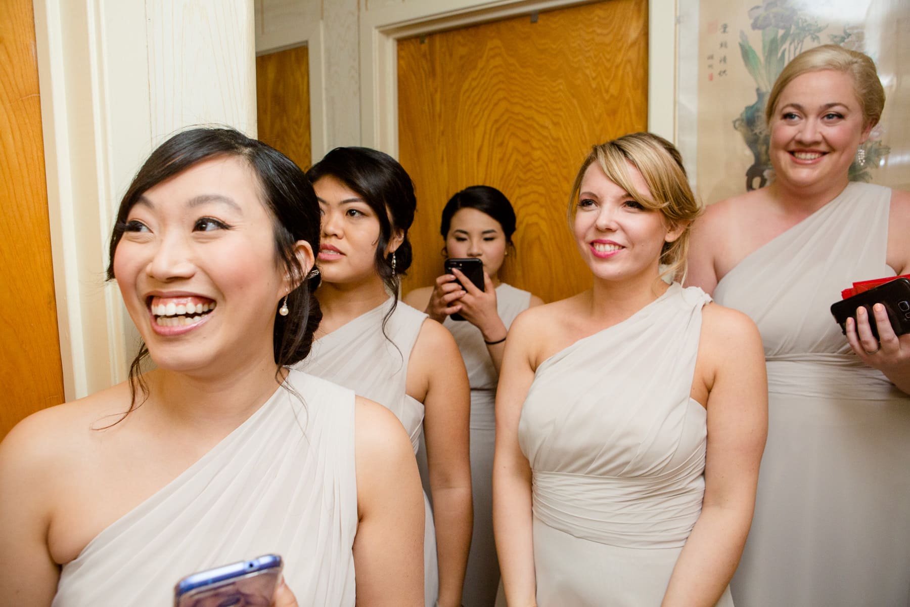 Bridesmaids standing in hallway watching door games