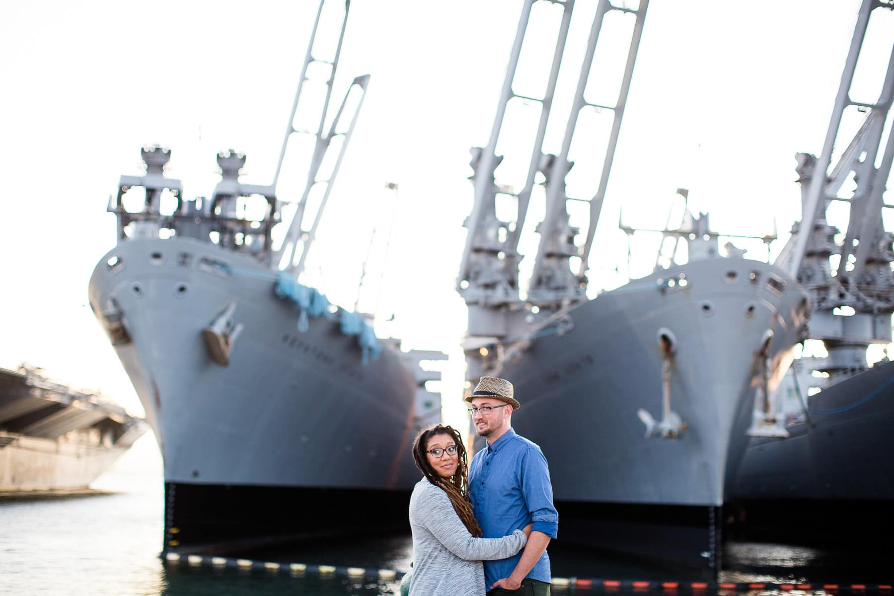 Man and woman embracing standing in front of two Navy Ships