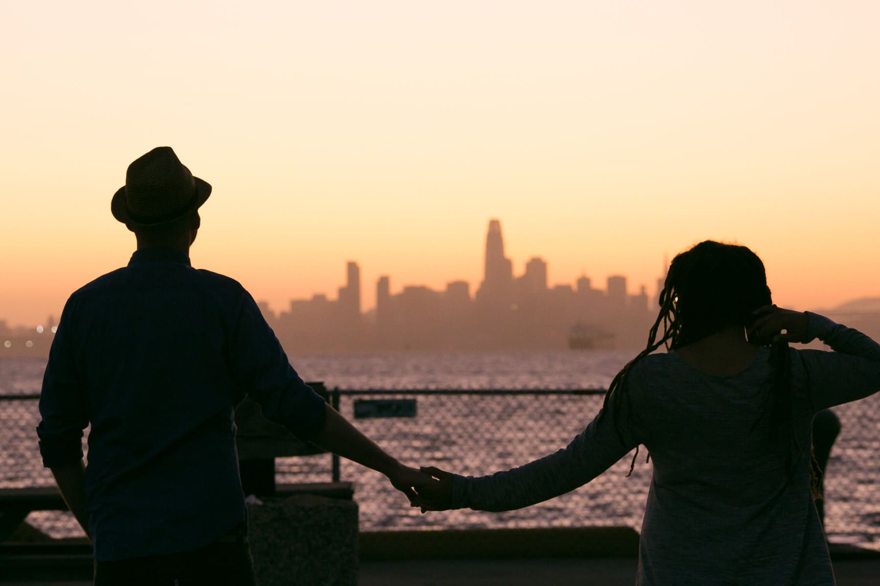 A couple silhouetted at sunset with San Francisco skyline in the background