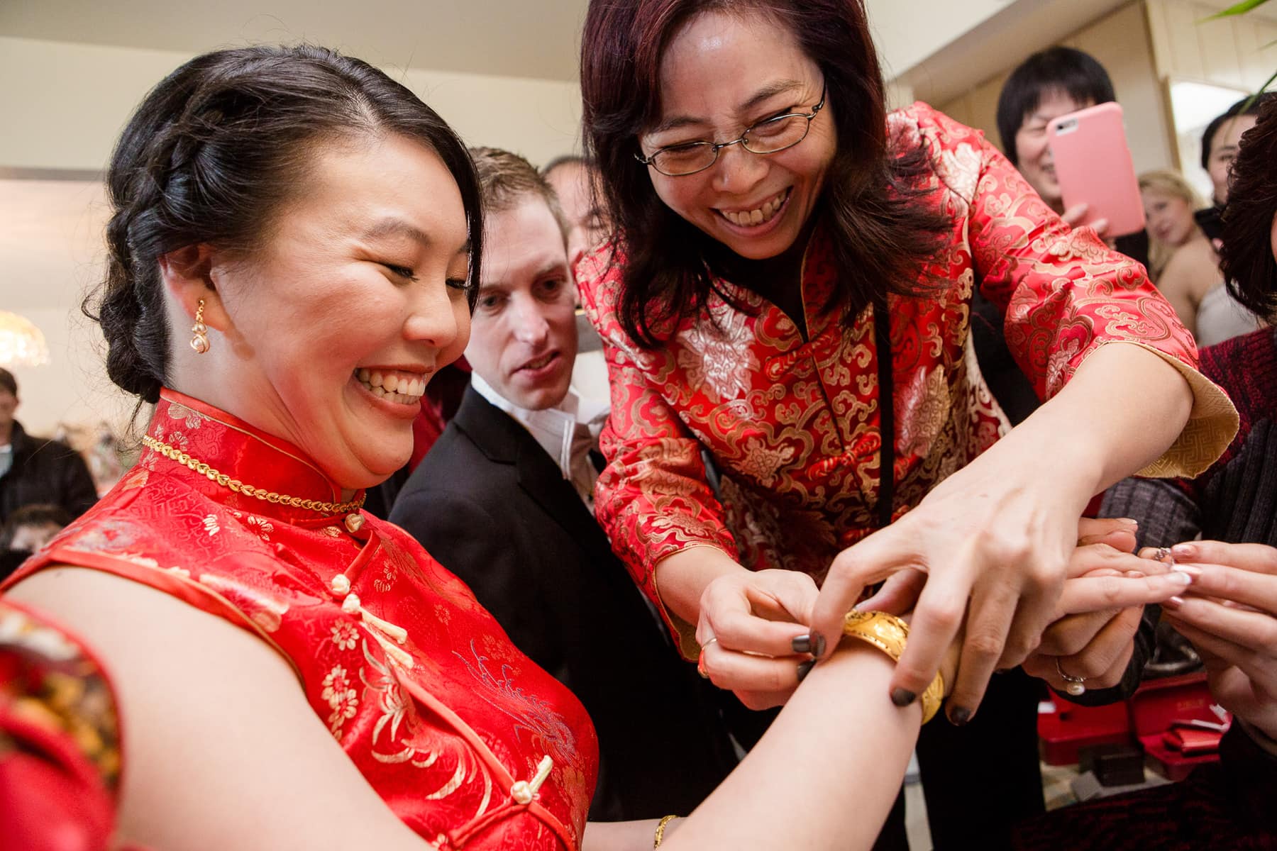 Bride smiling while receiving gold bracelet during tea ceremony