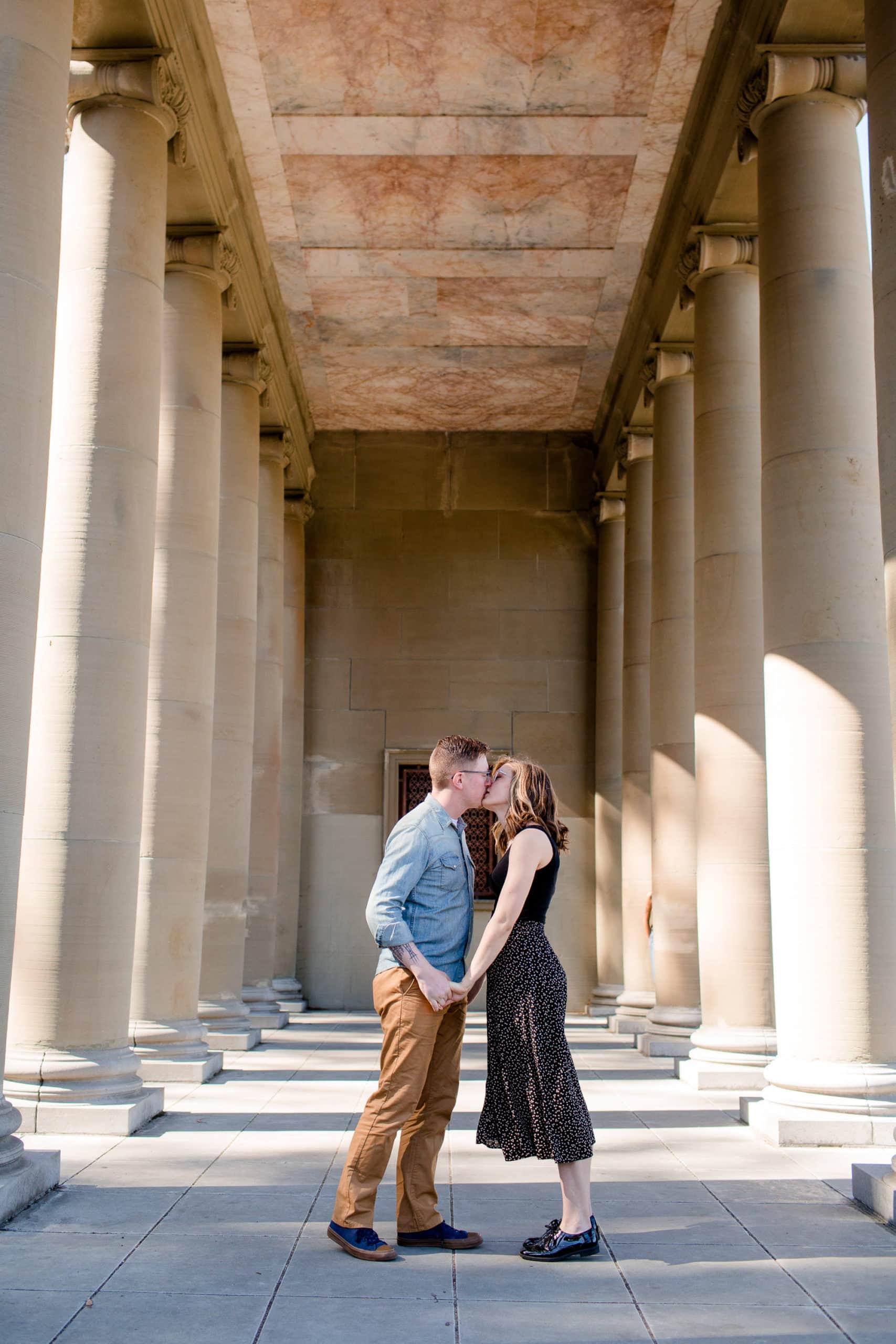Couple kissing standing in between rows of columns