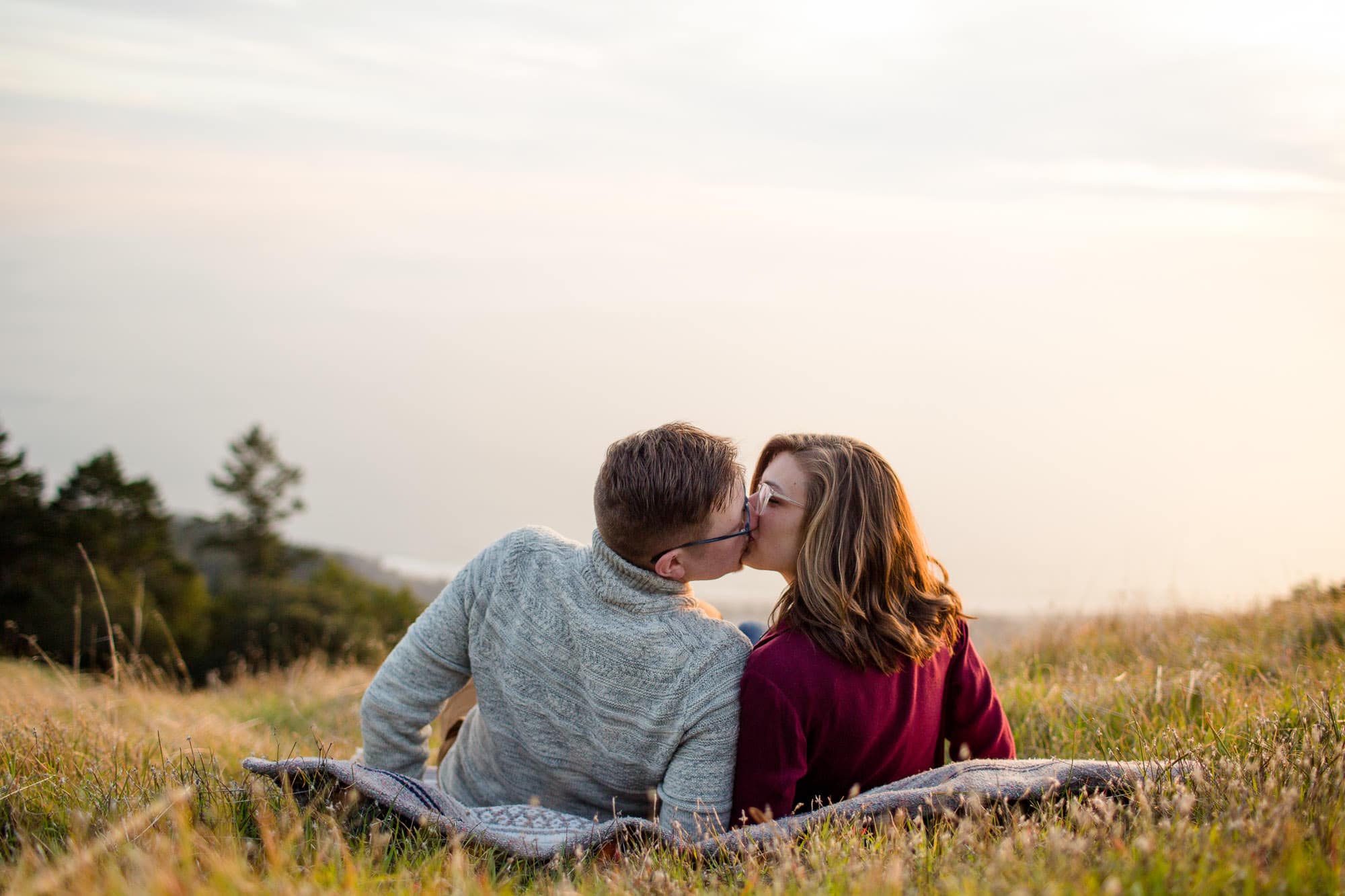 Couple on a blanket on a hill kissing at sunset