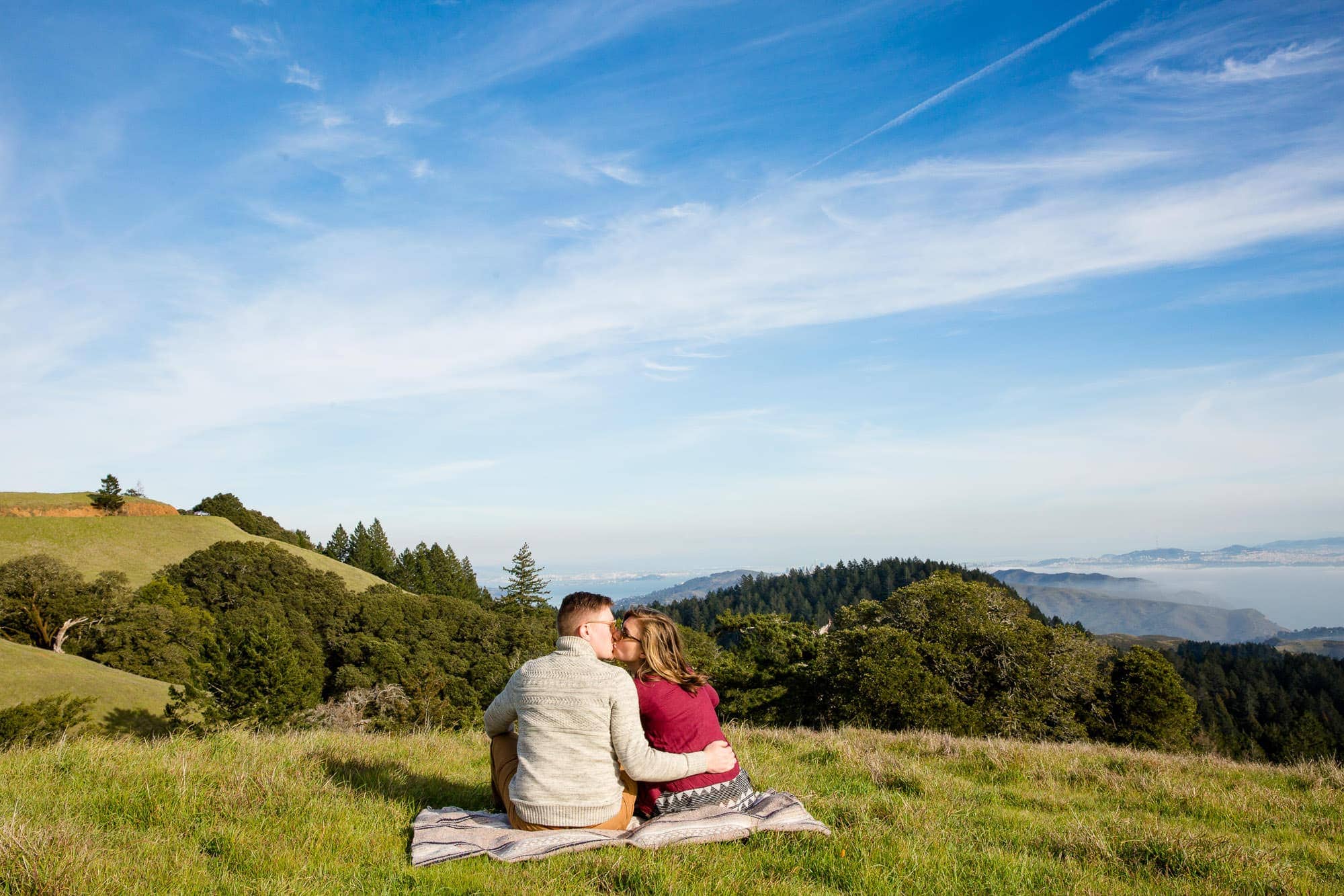 Sitting couple on a blanket on top of a grassy hill in Mt. Tamalpais