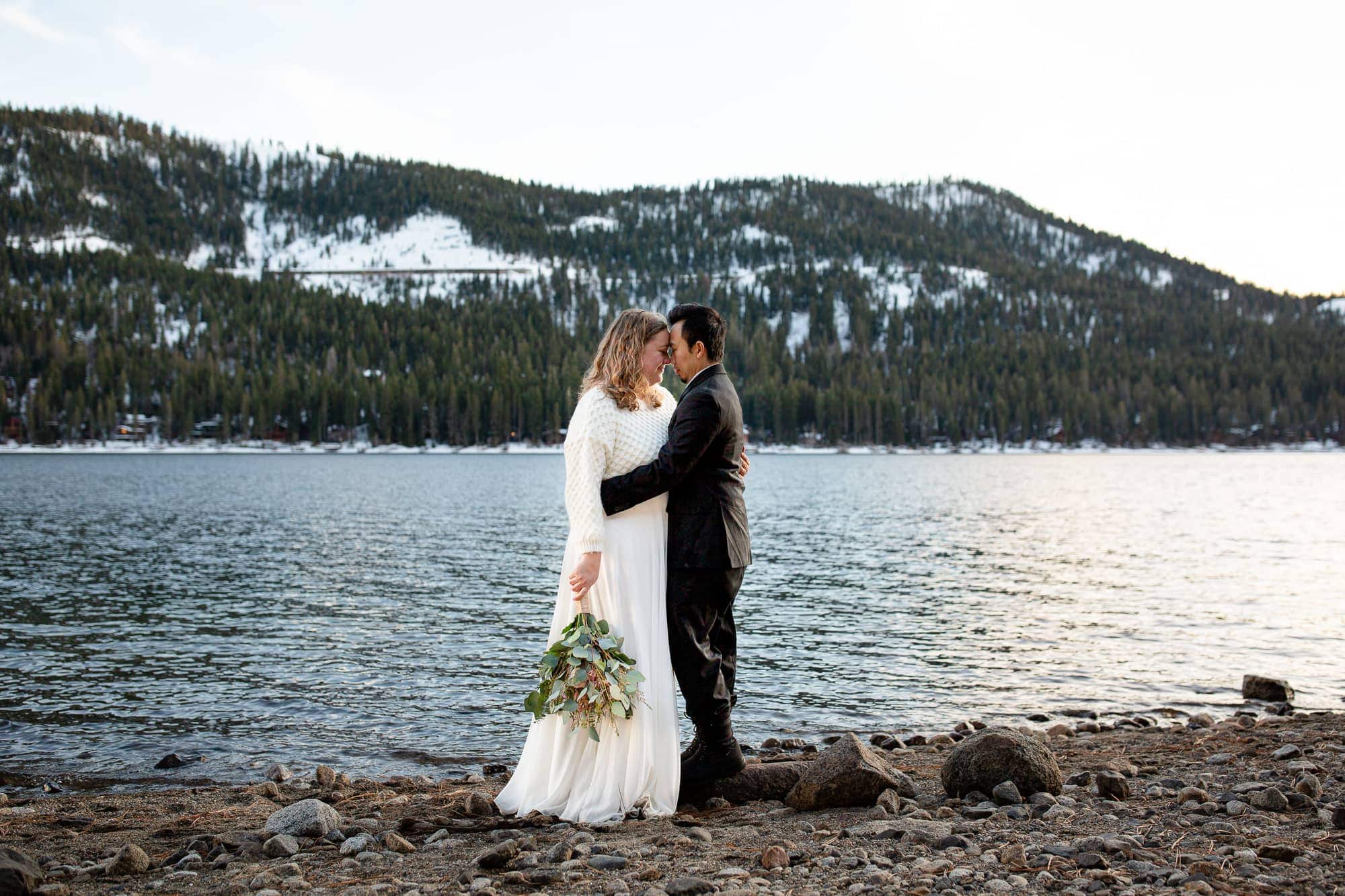 Couple with their foreheads touching in front of Donner Lake in wider
