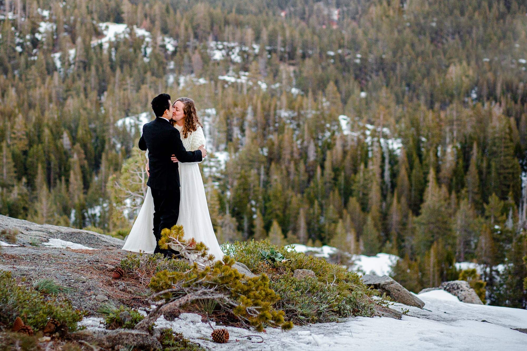 Bride and groom kissing in a snow covered forest