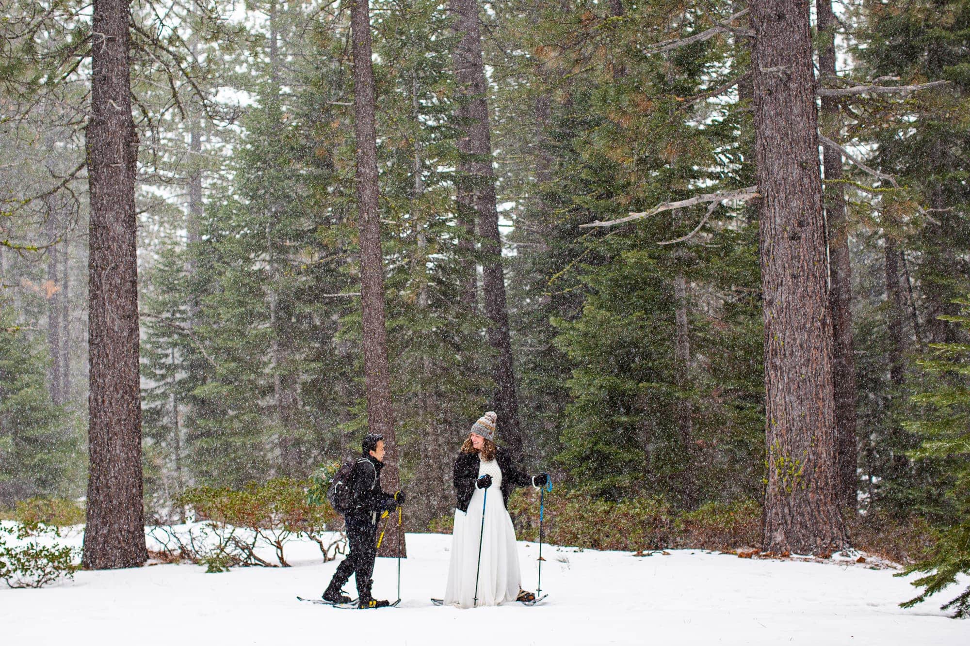Bride and groom snowshoeing in wedding clothes in a snow filled forest in Tahoe