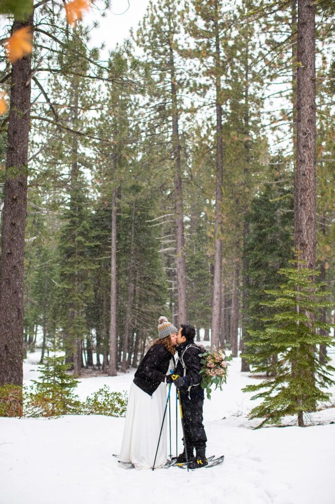 Husband and wife kissing in the snow in the forest