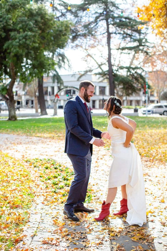 Bride showing the groom her red cowboy boots during a first look in a park in december